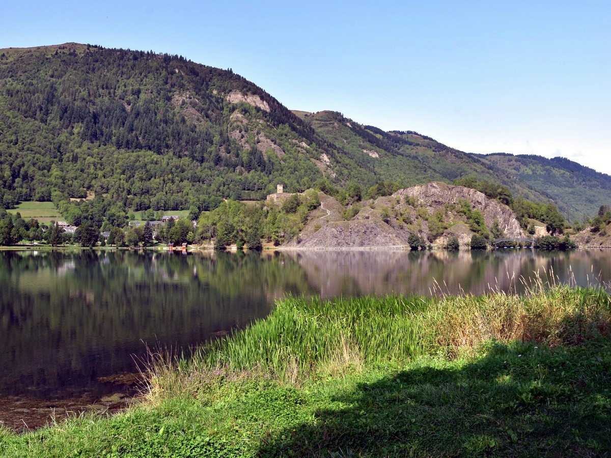 View over the castle and the ancient slate quarry from the east bank on the Lac de Loudenvielle Hike in French Pyrenees