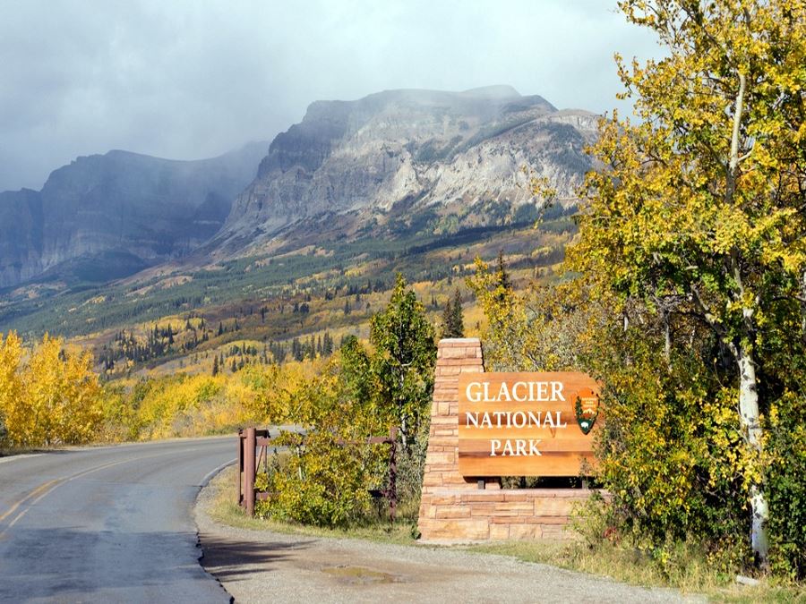 The sun hits a sign marking the entry to Glacier National Park