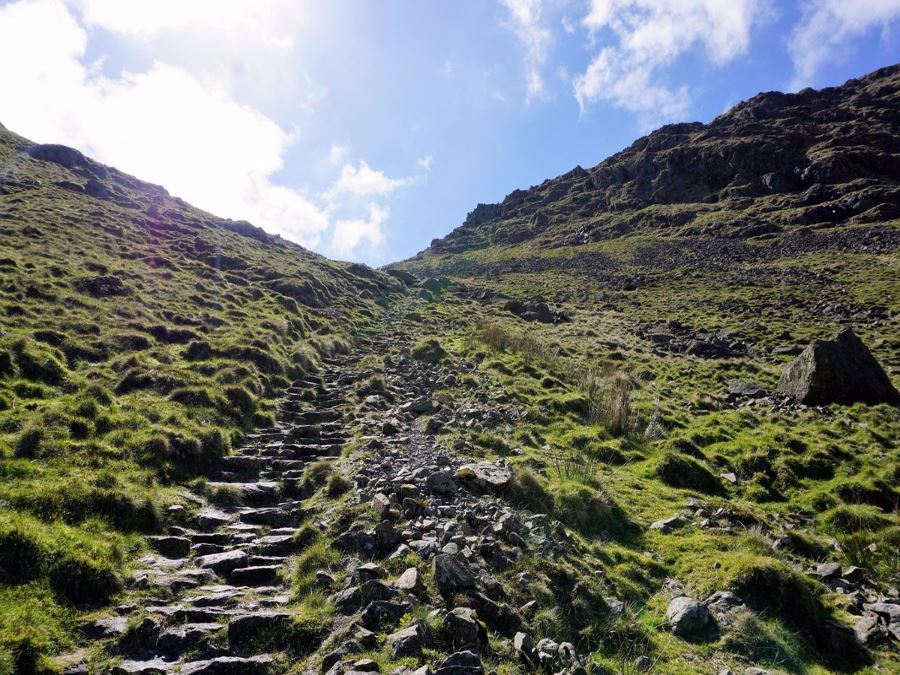 Climbing steps up to saddle below Thornthwaite Crag on the Roman High Street Circuit Hike in Lake District, England