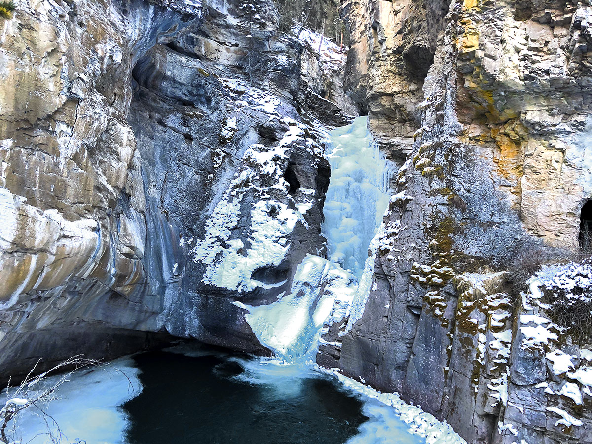 Lower Johnston Falls in winter covered in ice on Johnston Canyon snowshoe trail in Banff National Park