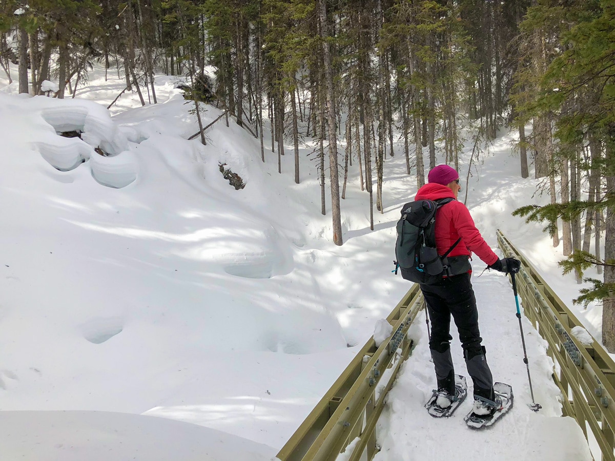 Crossing the bridge over Sarrail Creek on Beginning of Rawson Lake snowshoe trail in Kananaskis near Canmore