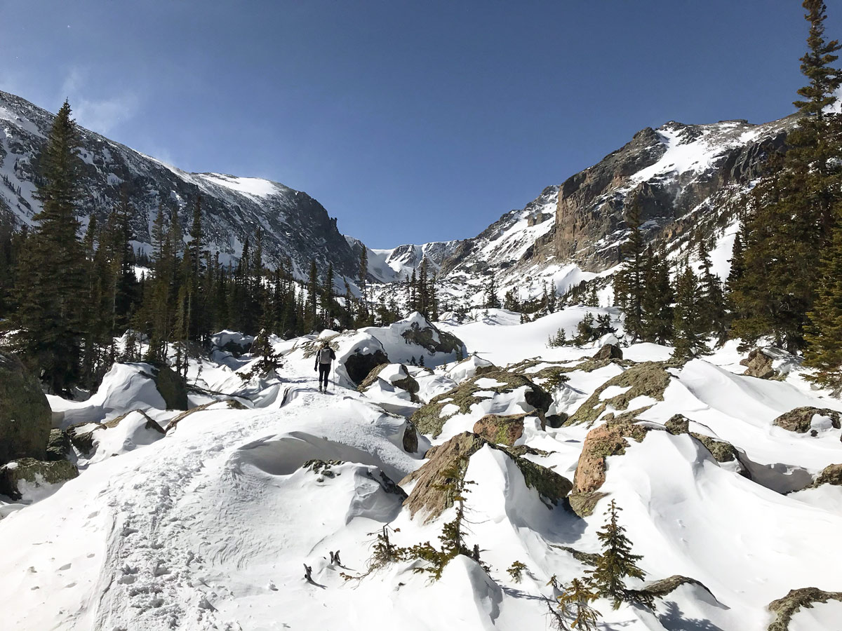 Hiking through the snow on Lake Haiyaha snowshoe trail in Rocky Mountain National Park, Colorado