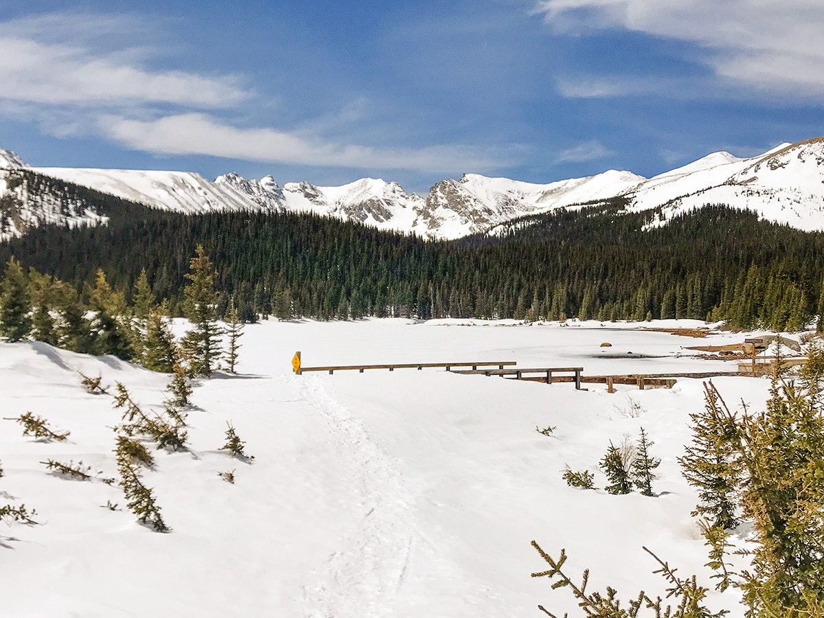 Lake covered by ice and snow on Brainard Lake snowshoe trail in Indian Peaks, Colorado