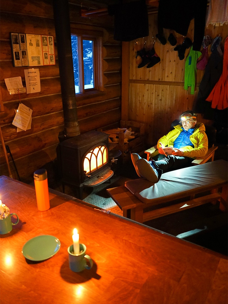 Reading and candlelight at Elk Lakes Cabin on Elk Lakes Backcountry Skiing Adventure