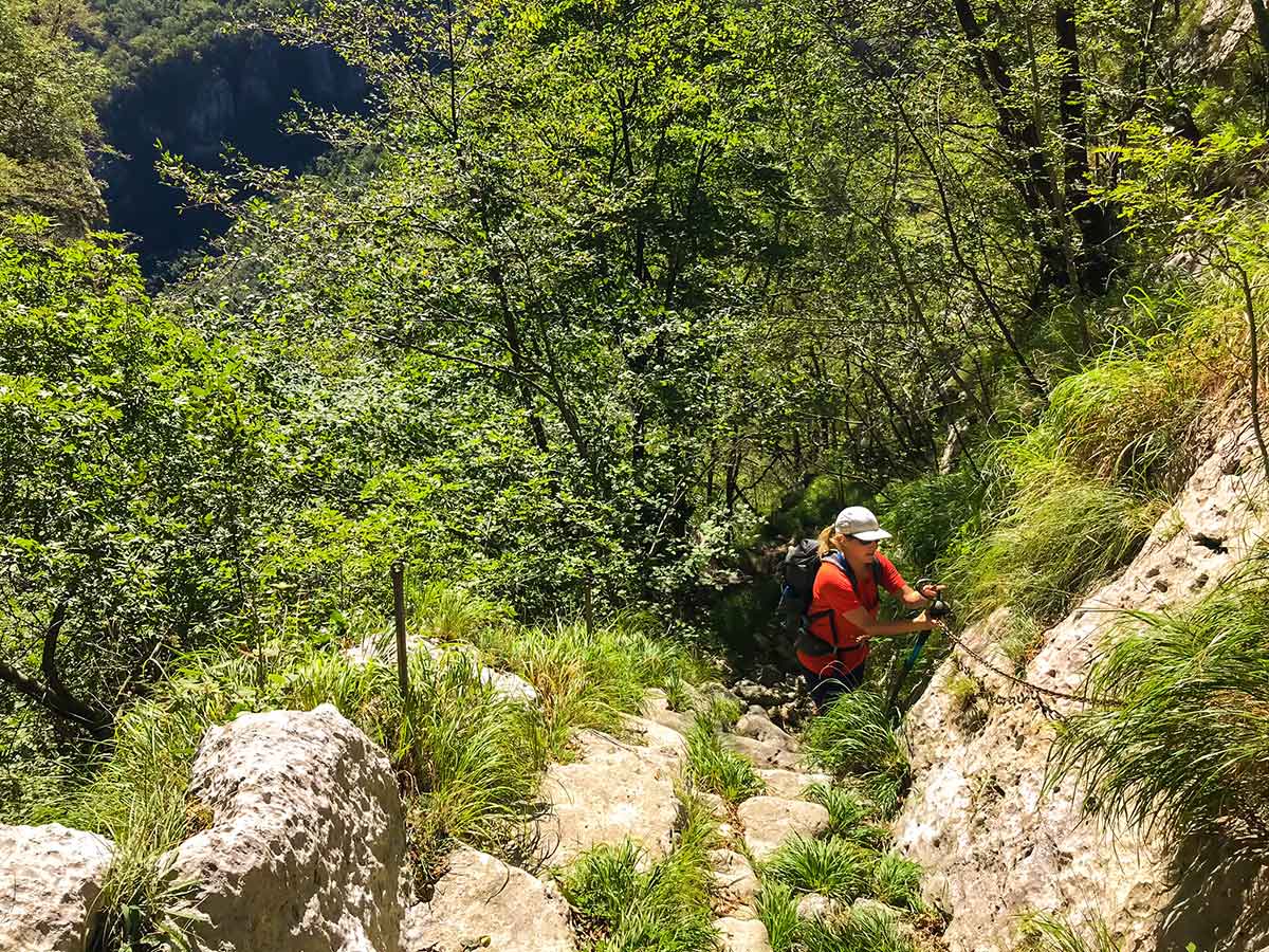 Hiker ascending with the help of chains on Monte Croce Hike in Tuscany