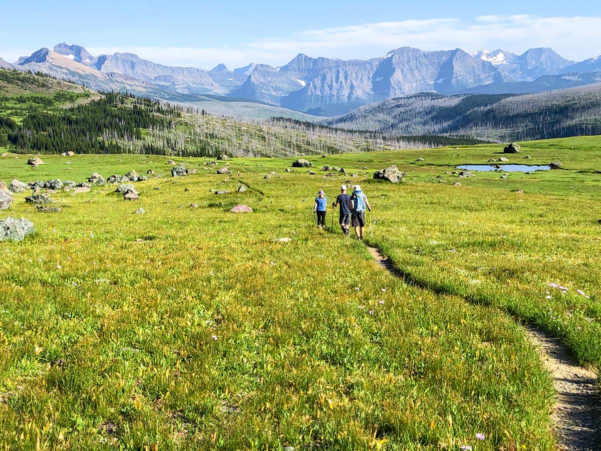 Hiking through the meadow surrounded by mountains on North Circle Backpacking Trail in Glacier National Park