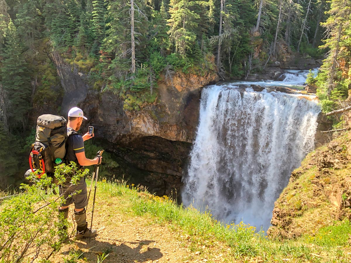 Taking pictures of beautiful waterfall on day 2 of hiking the North Circle Backpacking Trail in Glacier National Park
