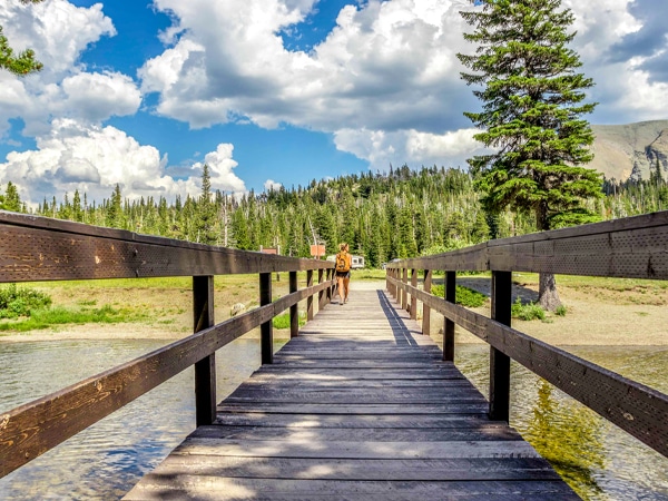 Crossing the footbridge on Pitamakan Dawson Loop Backpacking Trail in Glacier National Park