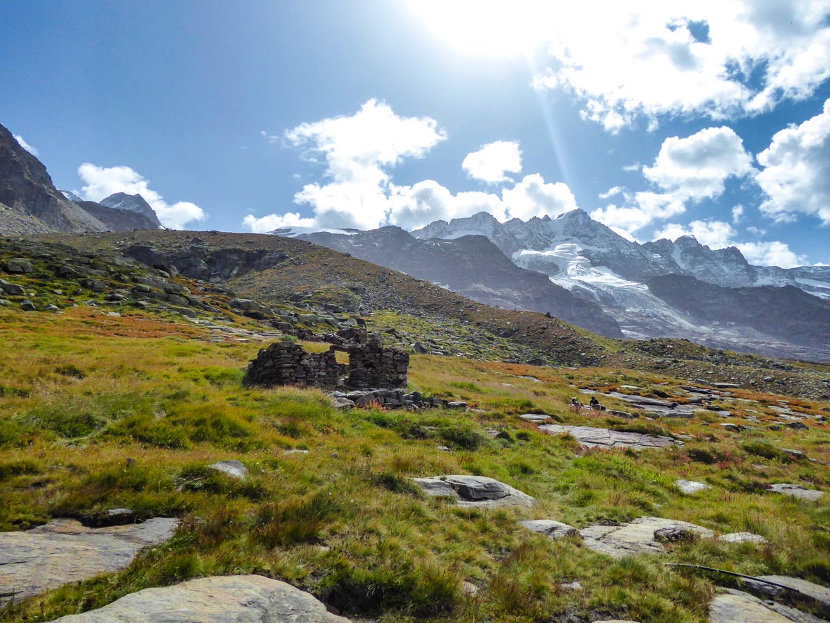 Ruins, meadow, glaciers and peaks on Alpe Money hike in Gran Paradiso National Park, Italy