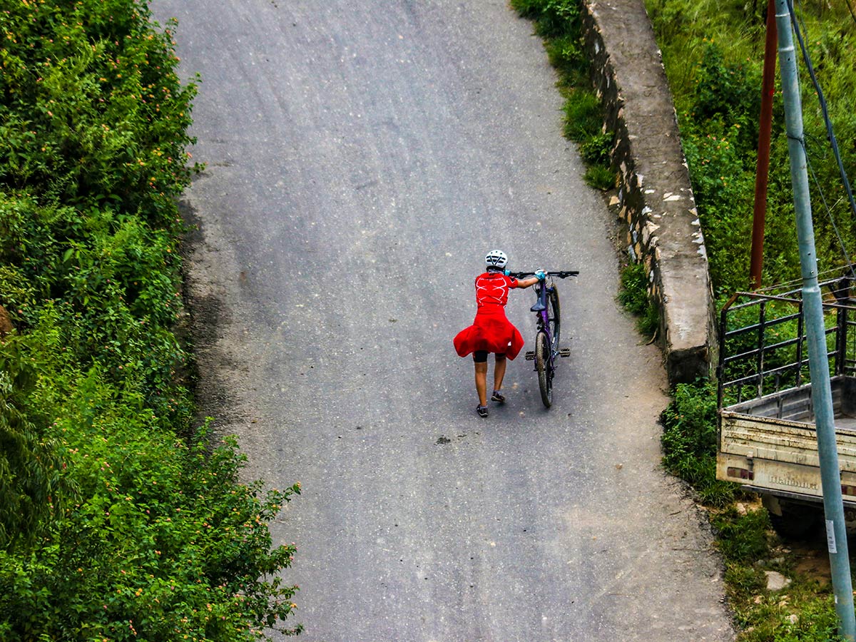 A rider pushing their bike in the uphill section