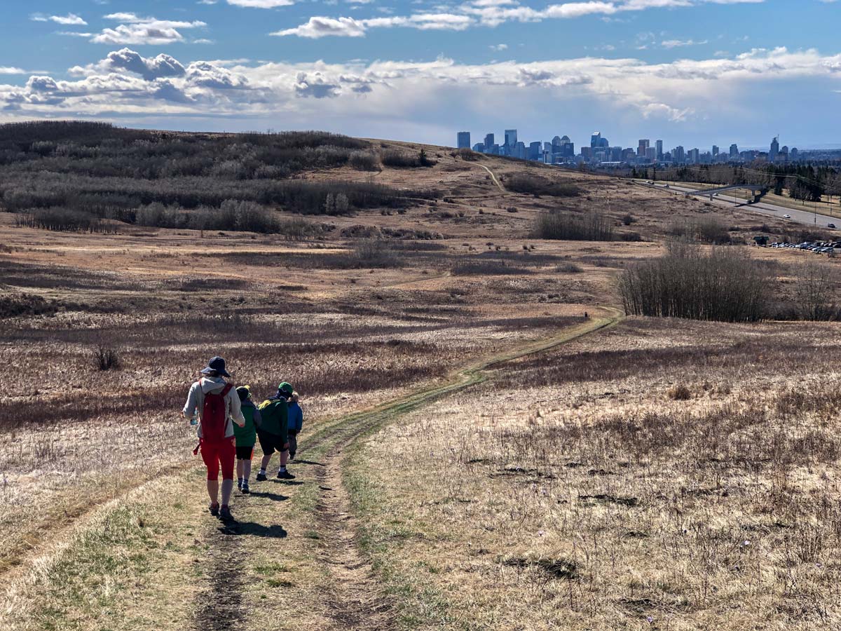 Returning to the parking lot from hiking trails in Nosehill Park in Calgary Alberta Canada with views of Calgary City Skyline