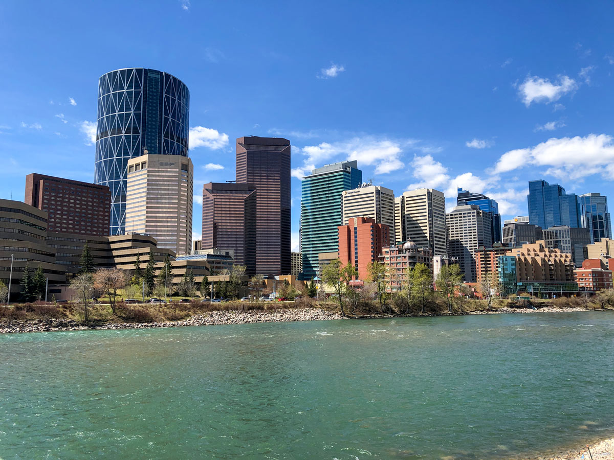 Turquoise Bow river waters below Calgary skyscrapers along city walk