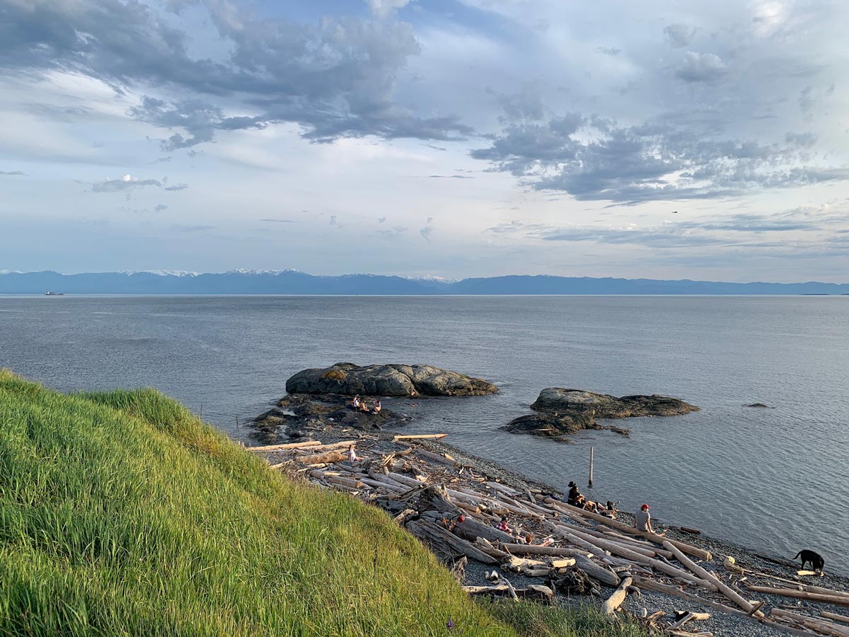 Beachgoers sit among the rocks and driftwood at Ogden poitn near Victoria