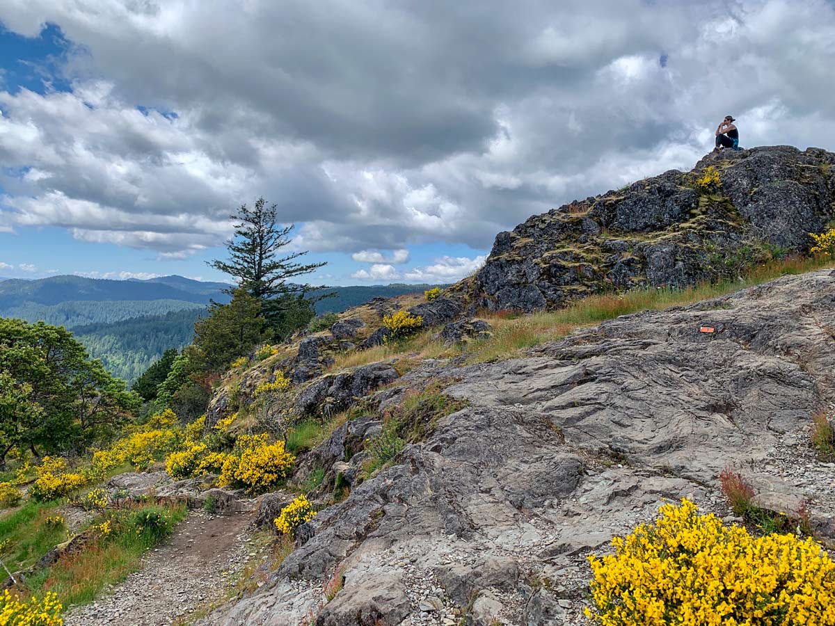 Woman admires views form Mount Finlayson while hiking near Victoria BC