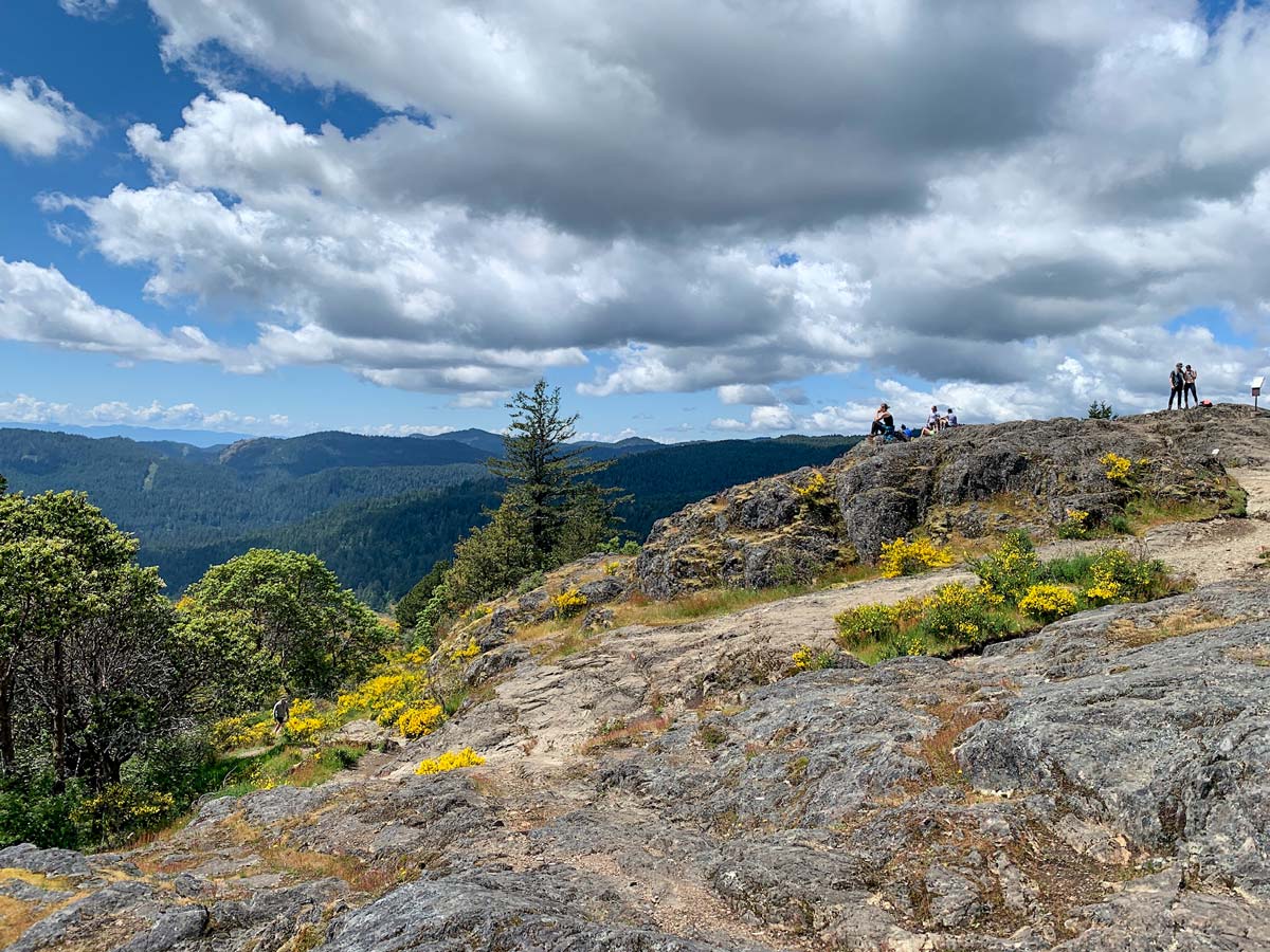 Group of hikers relax on the rocks of Mount Finlayson along one of the best hikes near near Victoria