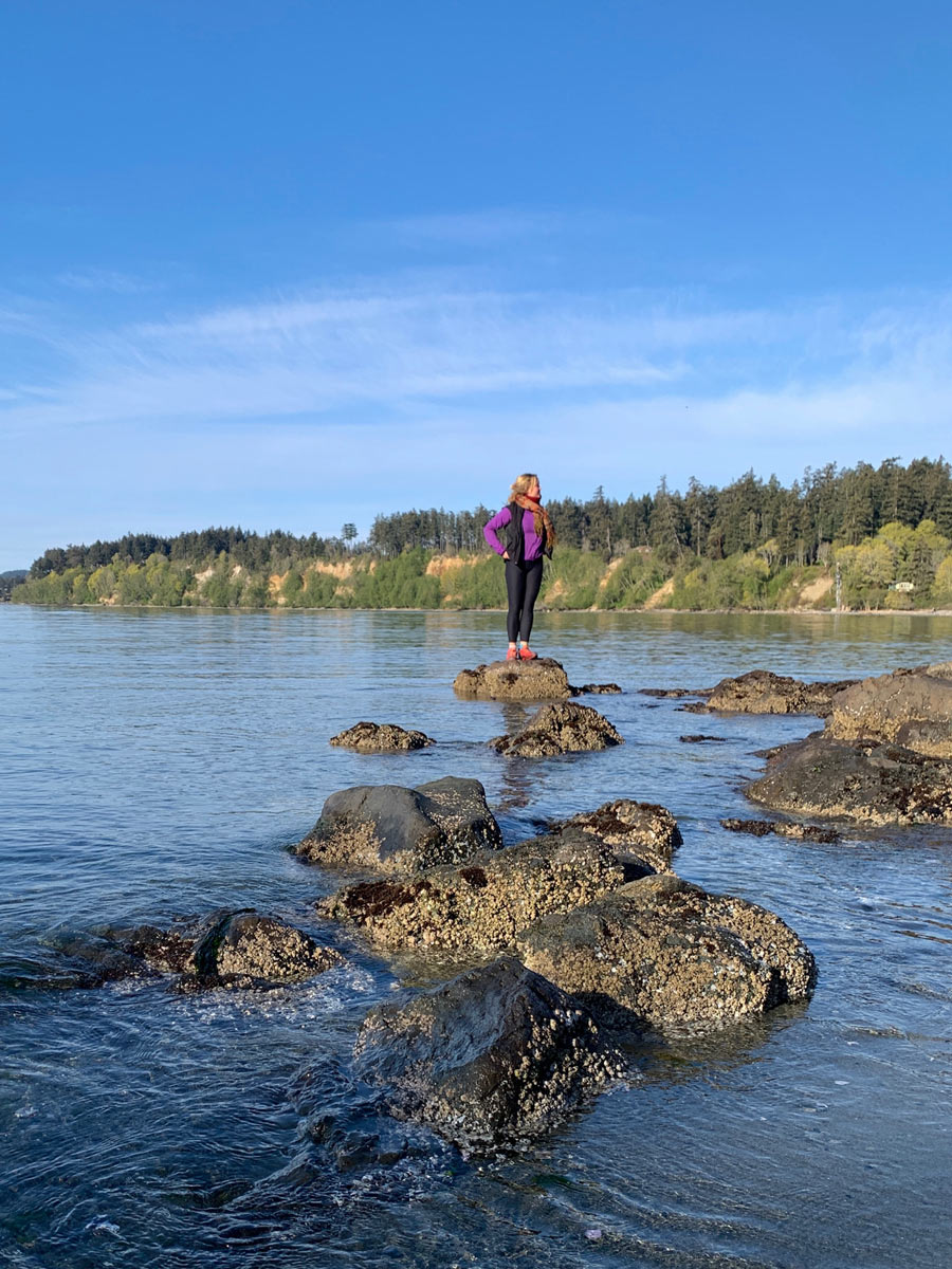 Hiker stands atop rock offshore of Wittys Lagoon along one of the best hikes near Victoria