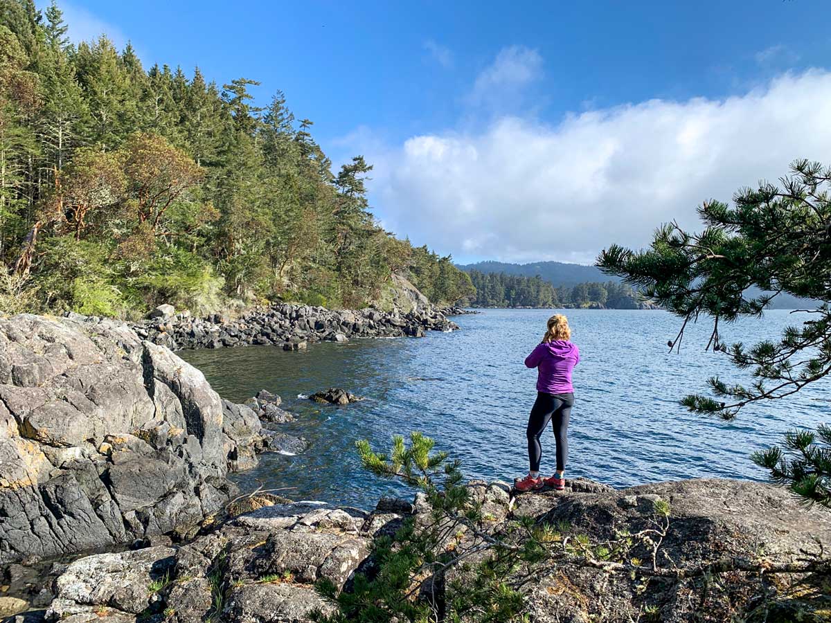 Woman looks out on beautiful ocean in Sooke while hiking near Victoria