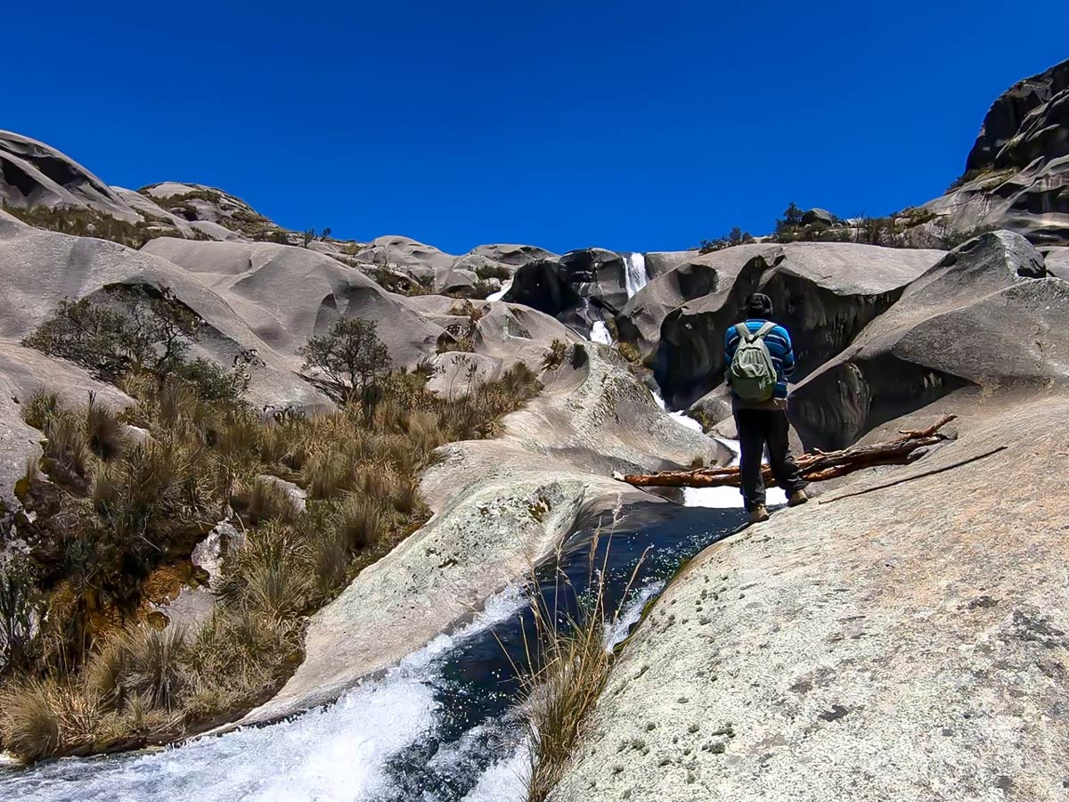 Hiker admires stone carved by river near Lake Auquicocha