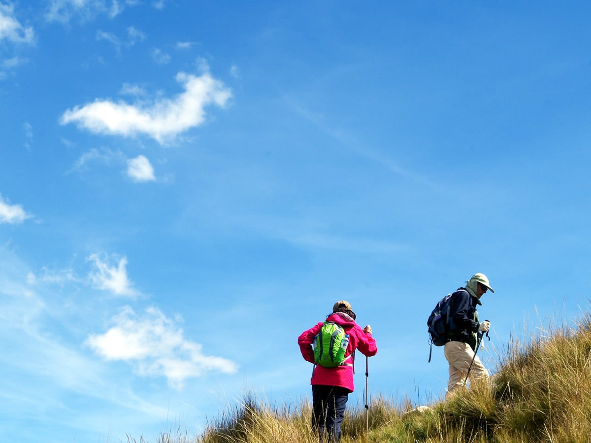 Hikers trek over grassy hill in Huaraz