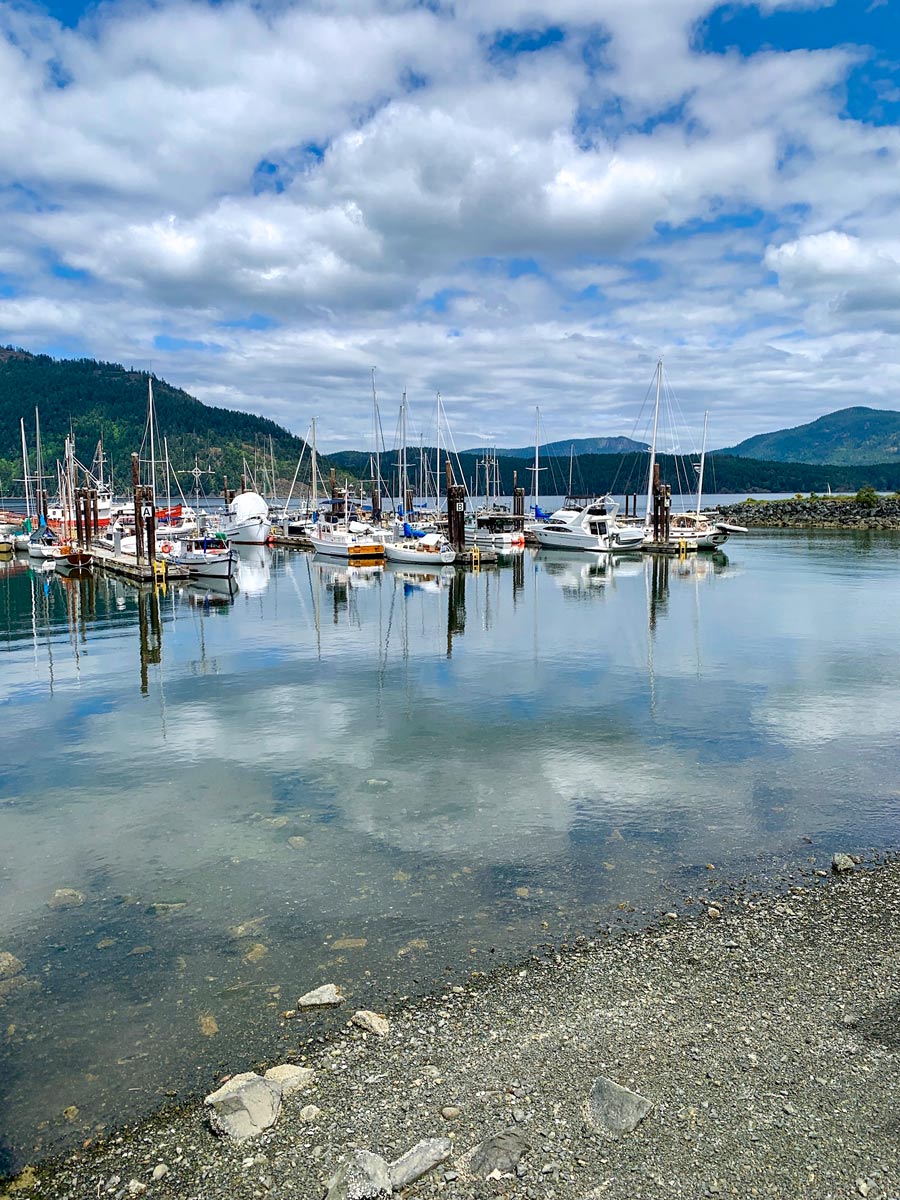 Sailboats moared in blue Pacific Ocean water along bike ride from Mill Bay to Cowichan Valley near Victoria