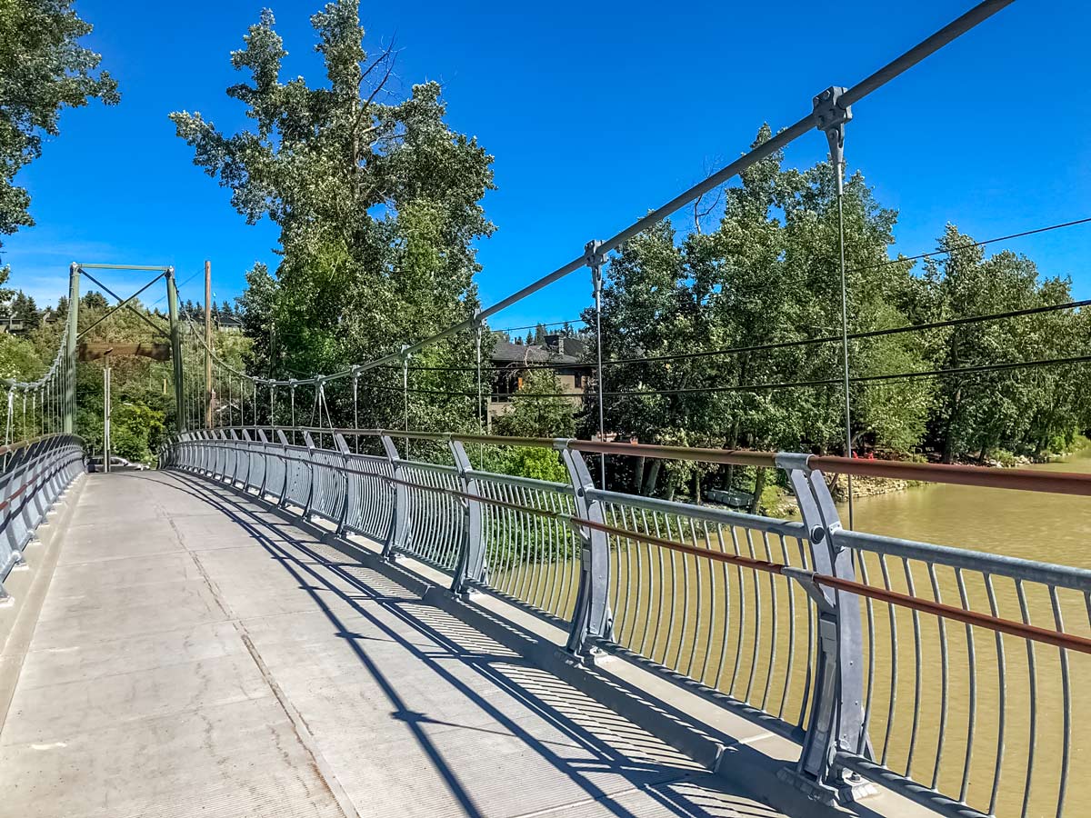 Cycling across pedestrian bridge along trail from South Calagry to Edworthy Park