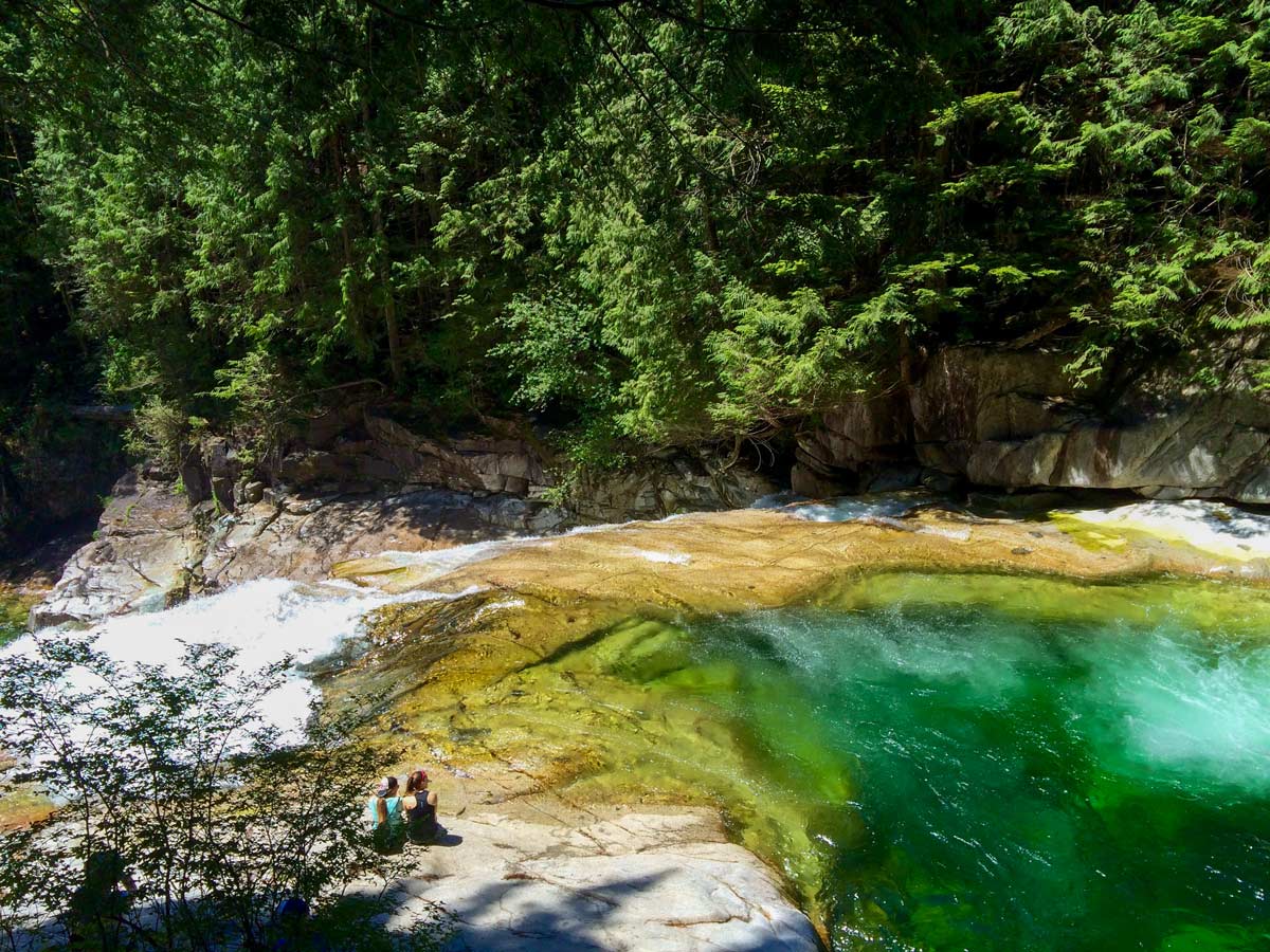 Hikers admiring turquoise waters of pools above Gold Creek Falls near Vancouver