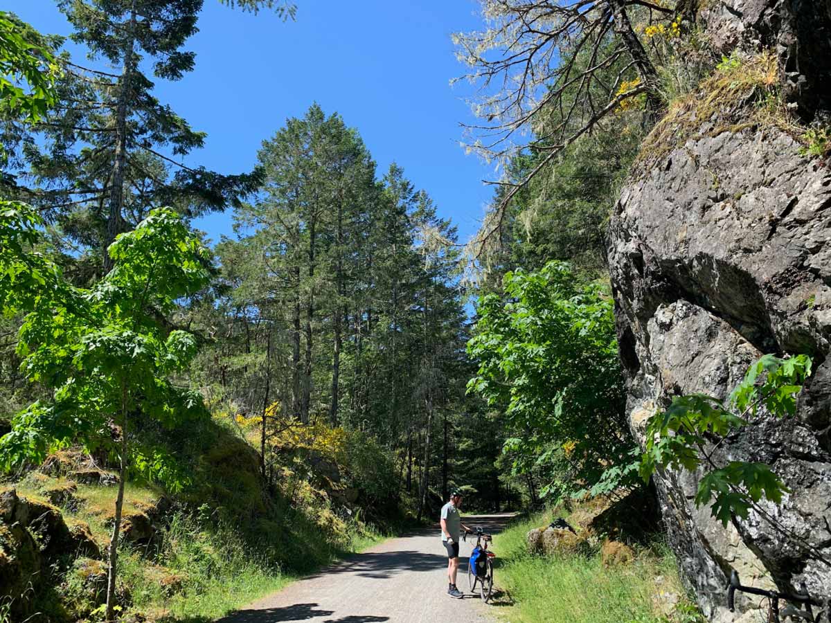 Cyclinst stops by rock bluffs along Goose to Sooke Potholes bike trail near Victoria