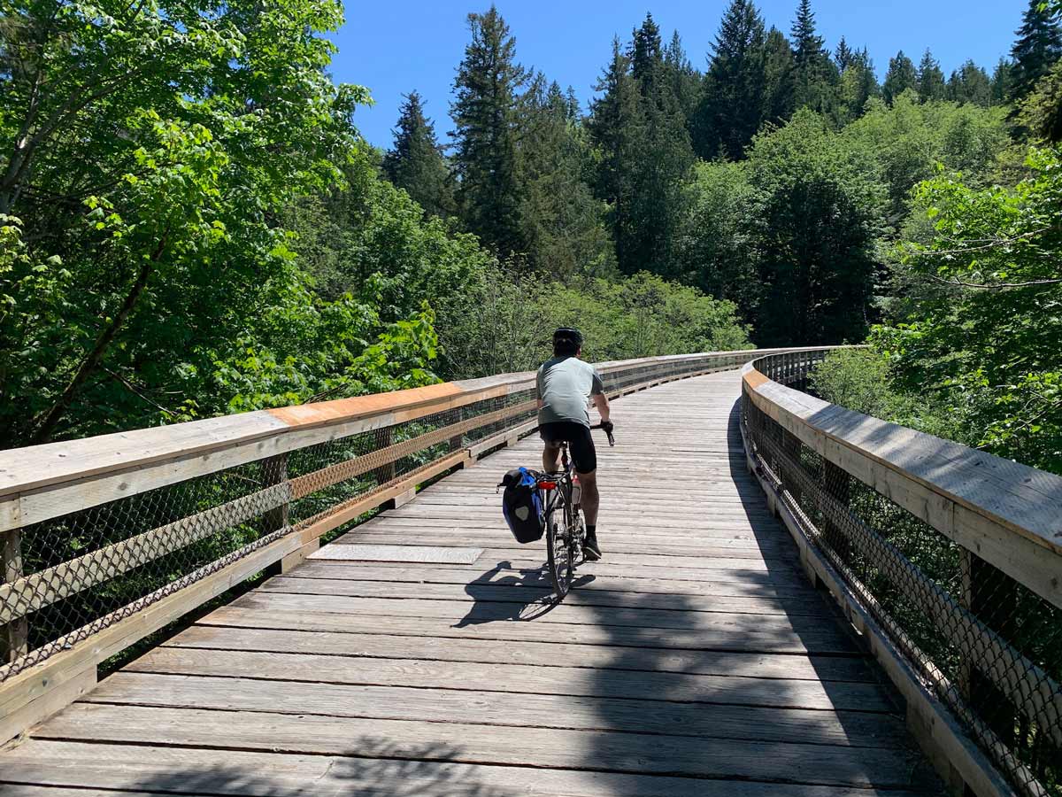 Biking along boardwalks through the forest on Peninsula Loop biking trail near Victoria BC
