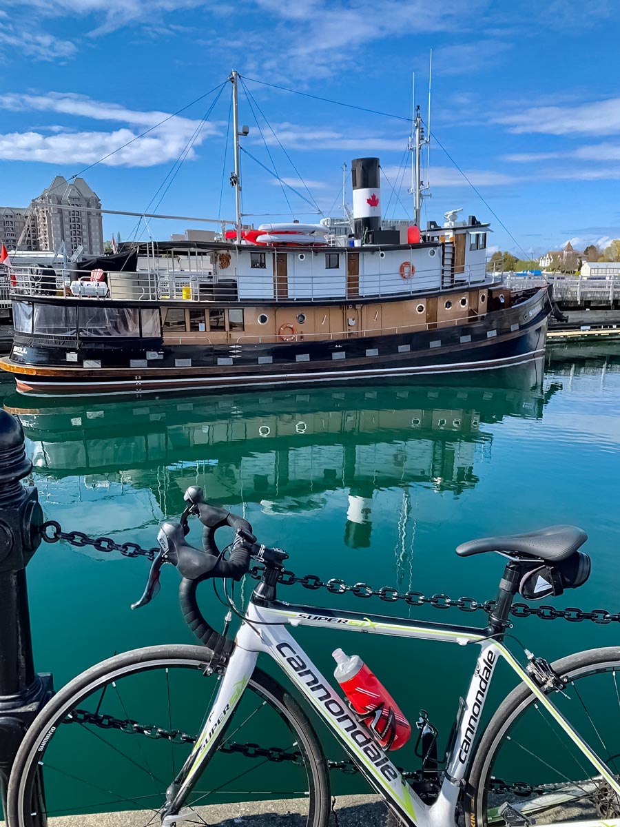 Bike and tugboat in turquoise ocean along Seaside Loop trail in Victoria BC