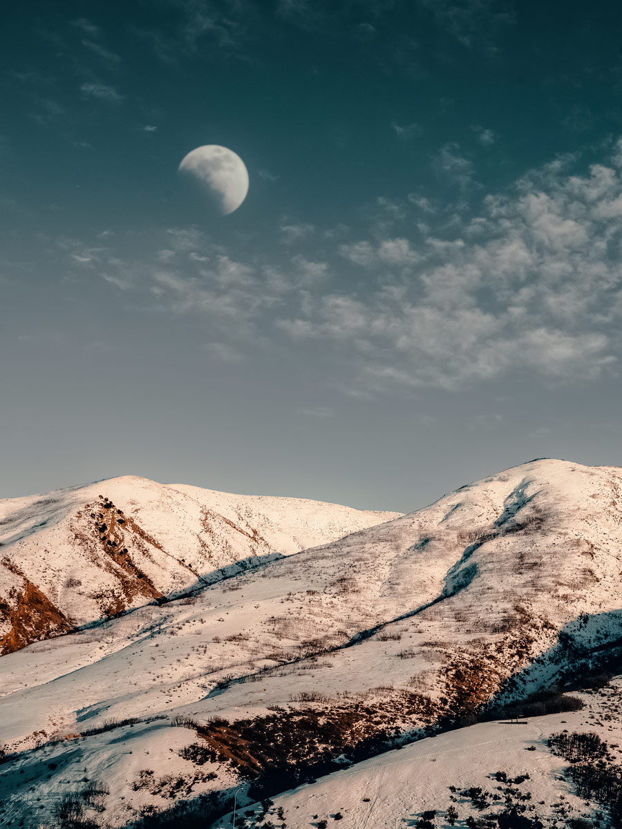 Afternoon moon sun over snowy hill mountains in Utah winter near Salt Lake City SLC