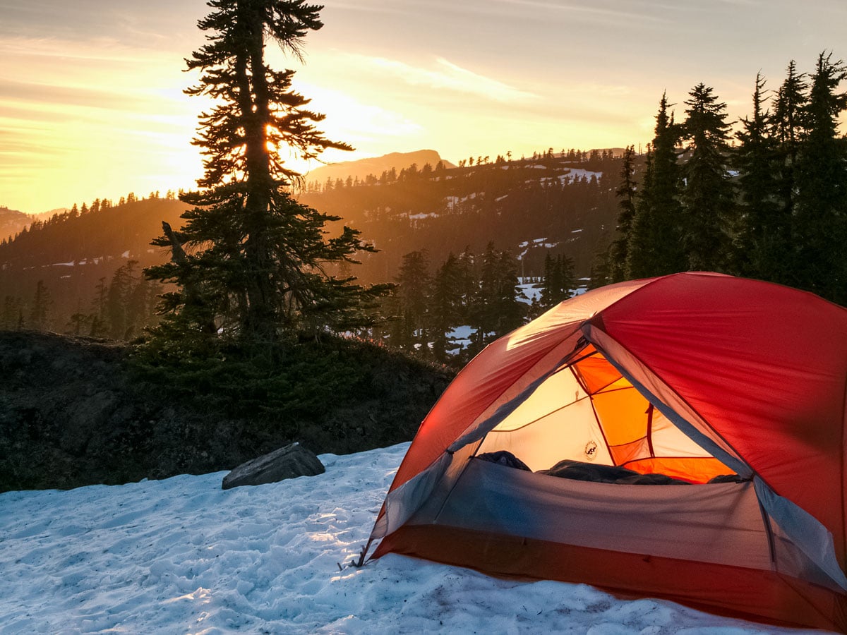 Sunset through trees cozy winter camping trip