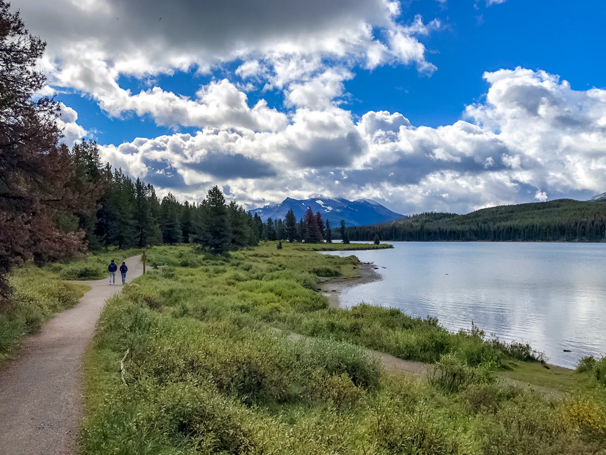 Couple walks pathway around Maligne Lake near beautiful Jasper Alberta Canada