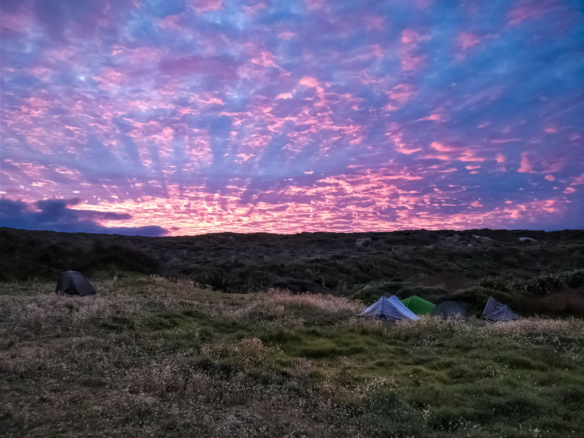 Stunning sunrise over tents campsite along Te Araroa trail New Zealand