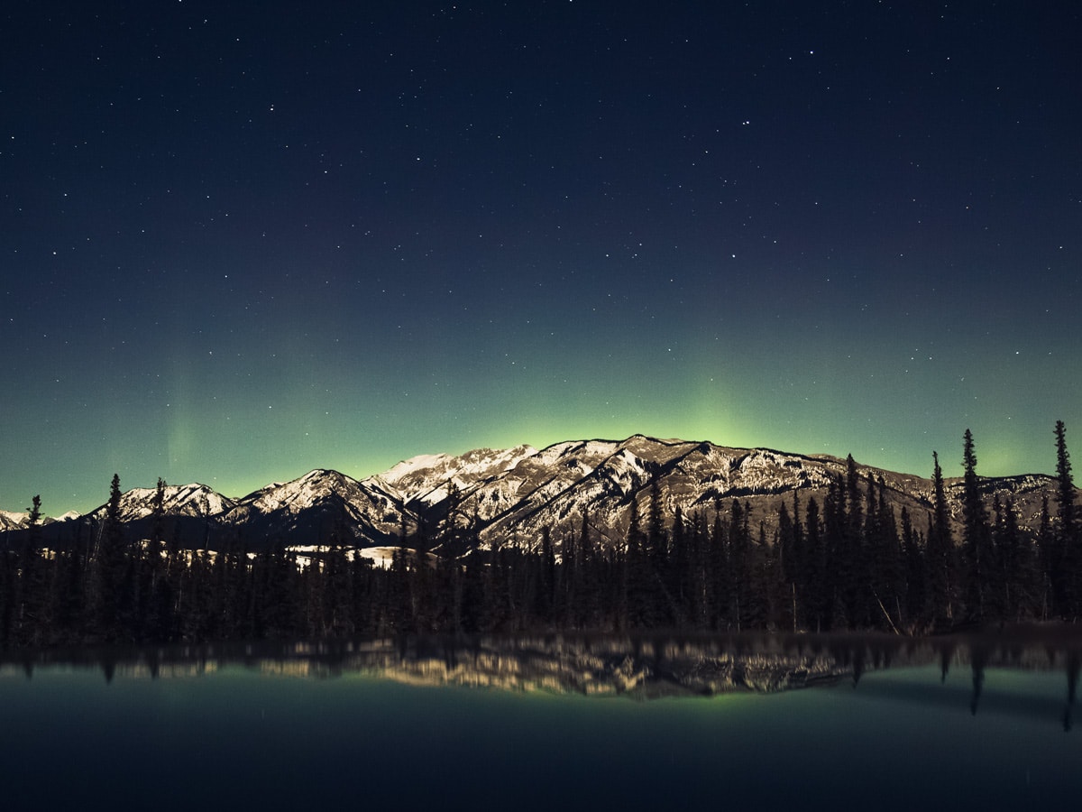 Starry night and Northern Lights over rocky mountains in Jasper Alberta Canada