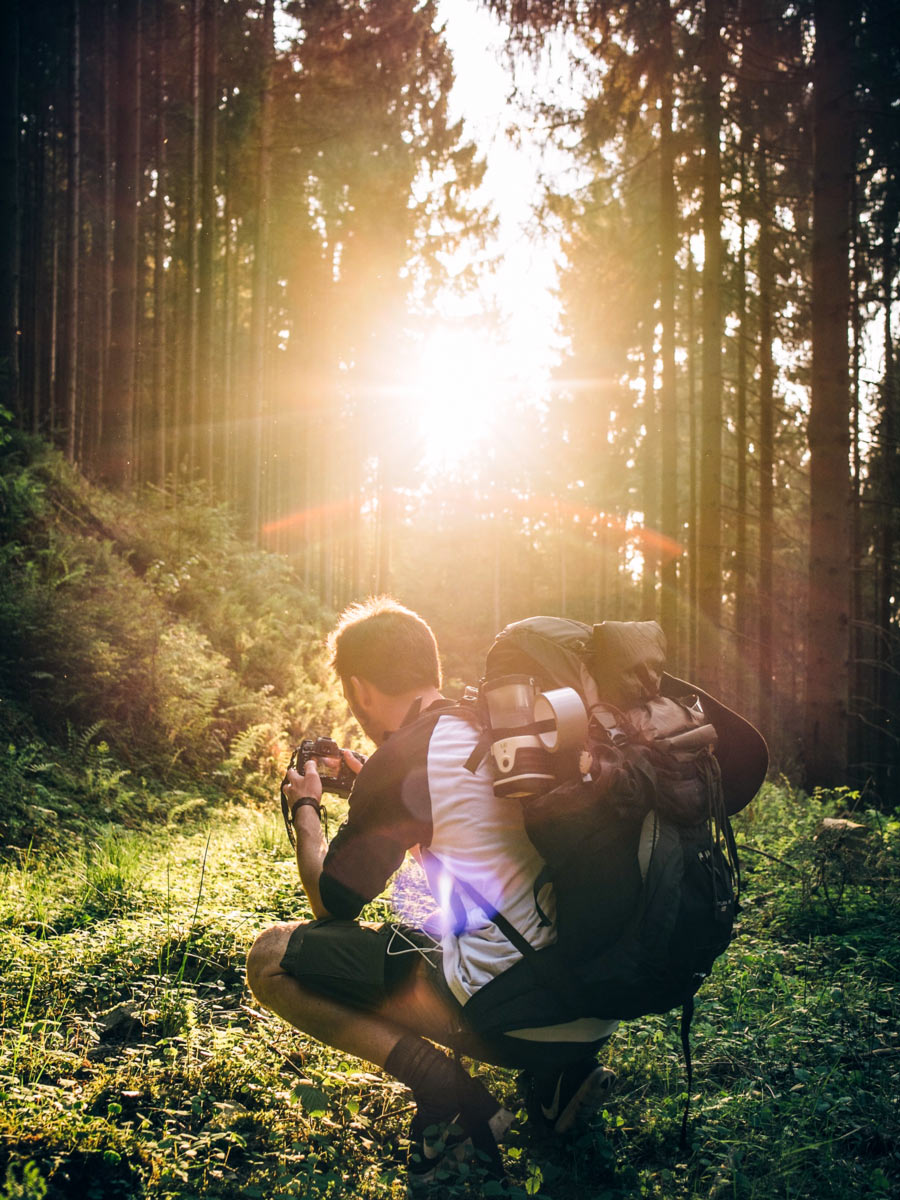 Photographer with camera hiking in the forest