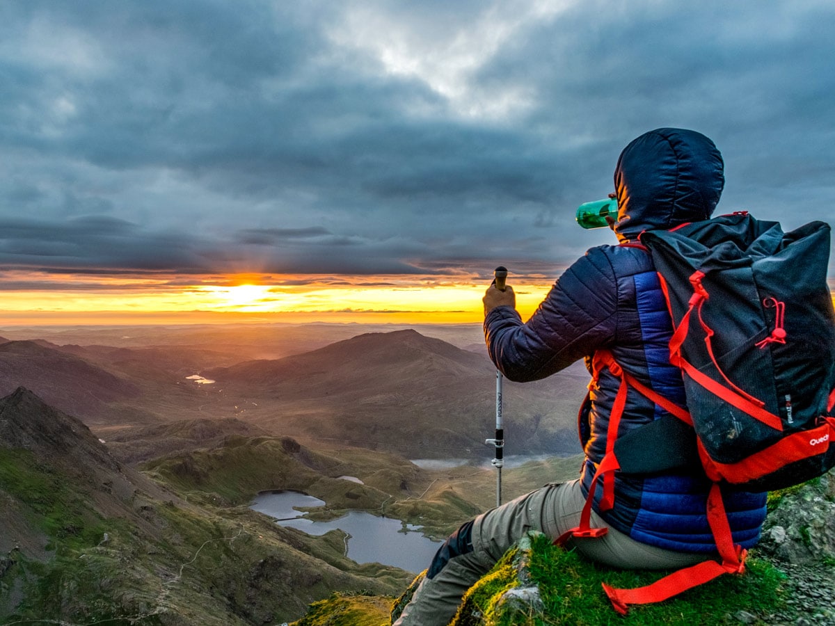 Hiker sitting on ledge watching sunset