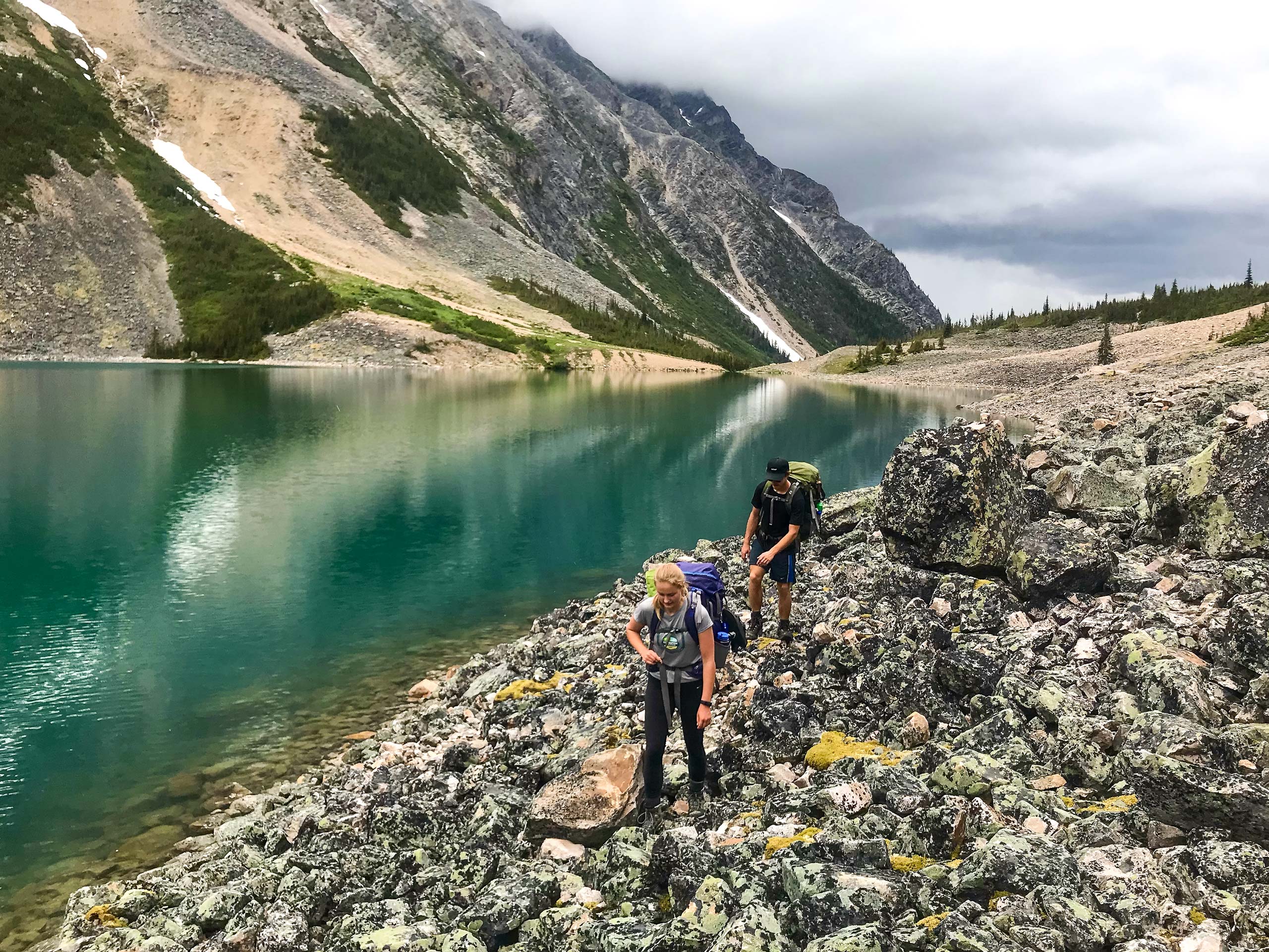 Backpackers hiking rock shores of aqua coloured Geraldine Lakes Jasper Canada