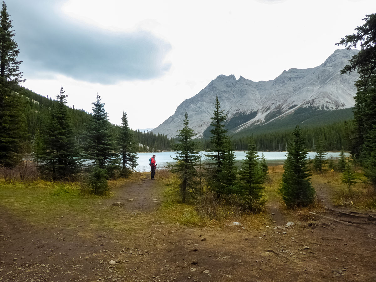 Hiker standing on lake shore along Edworthy Falls trail in Kananaskis Alberta