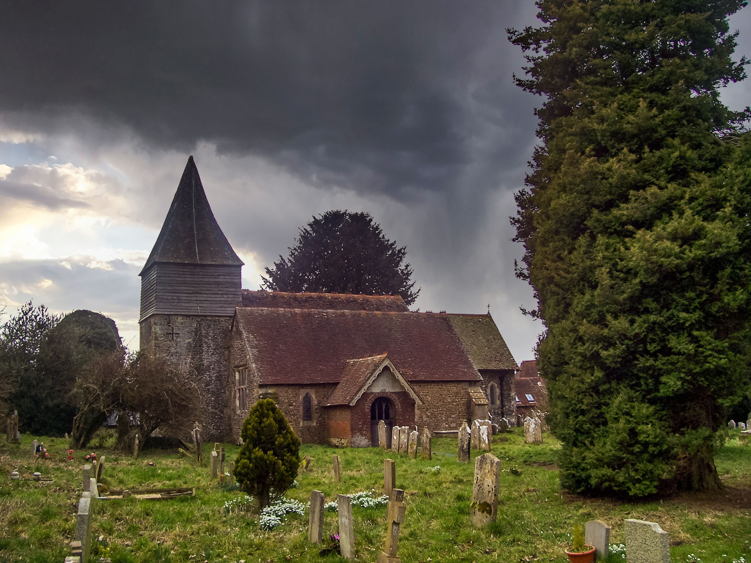 Storm clouds over old church graveyard walking Liss Hawkley and Steep walk in South Downs UK