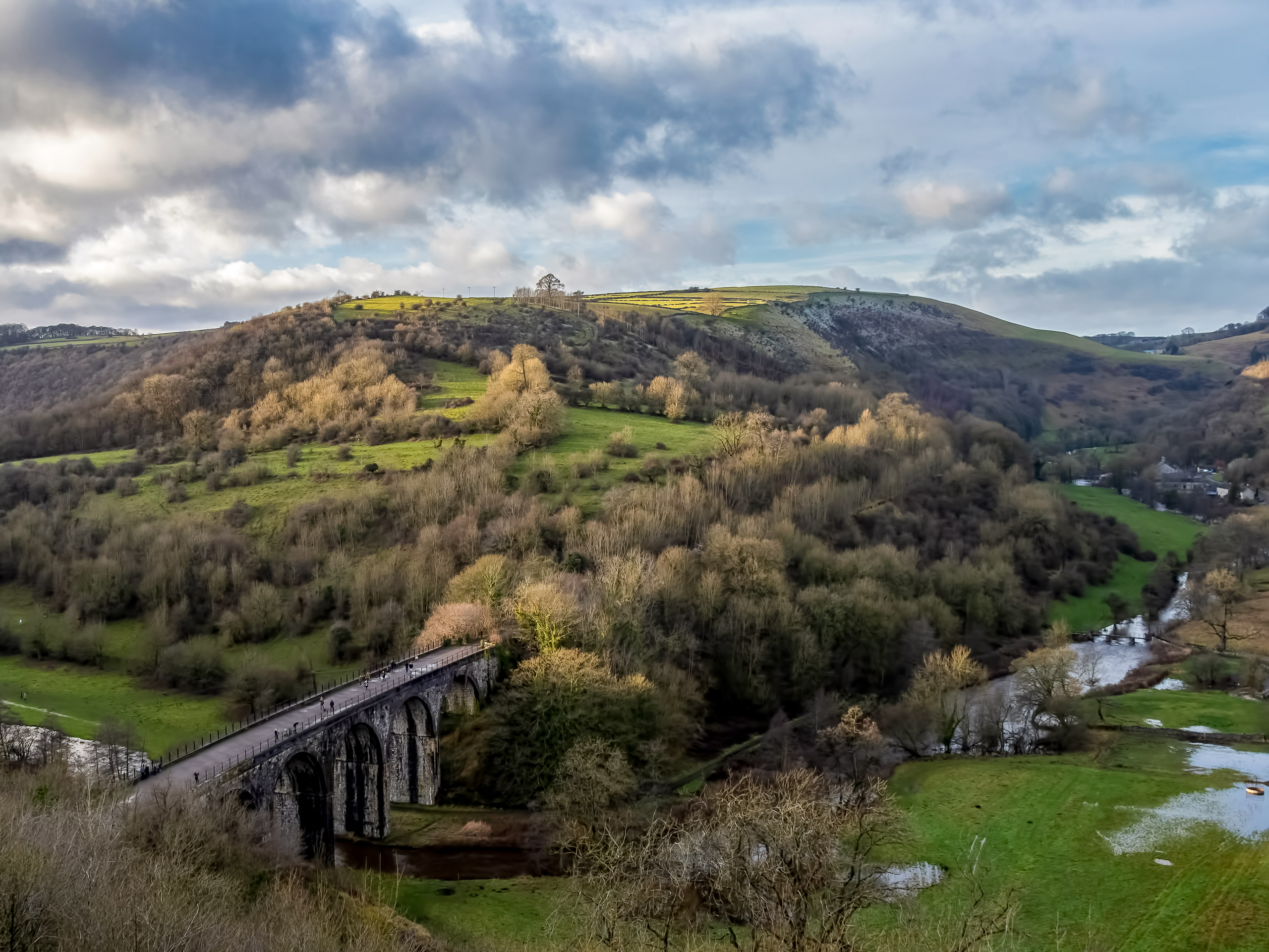 People walking on stone bridge over river along Monsal Dale Walk UK