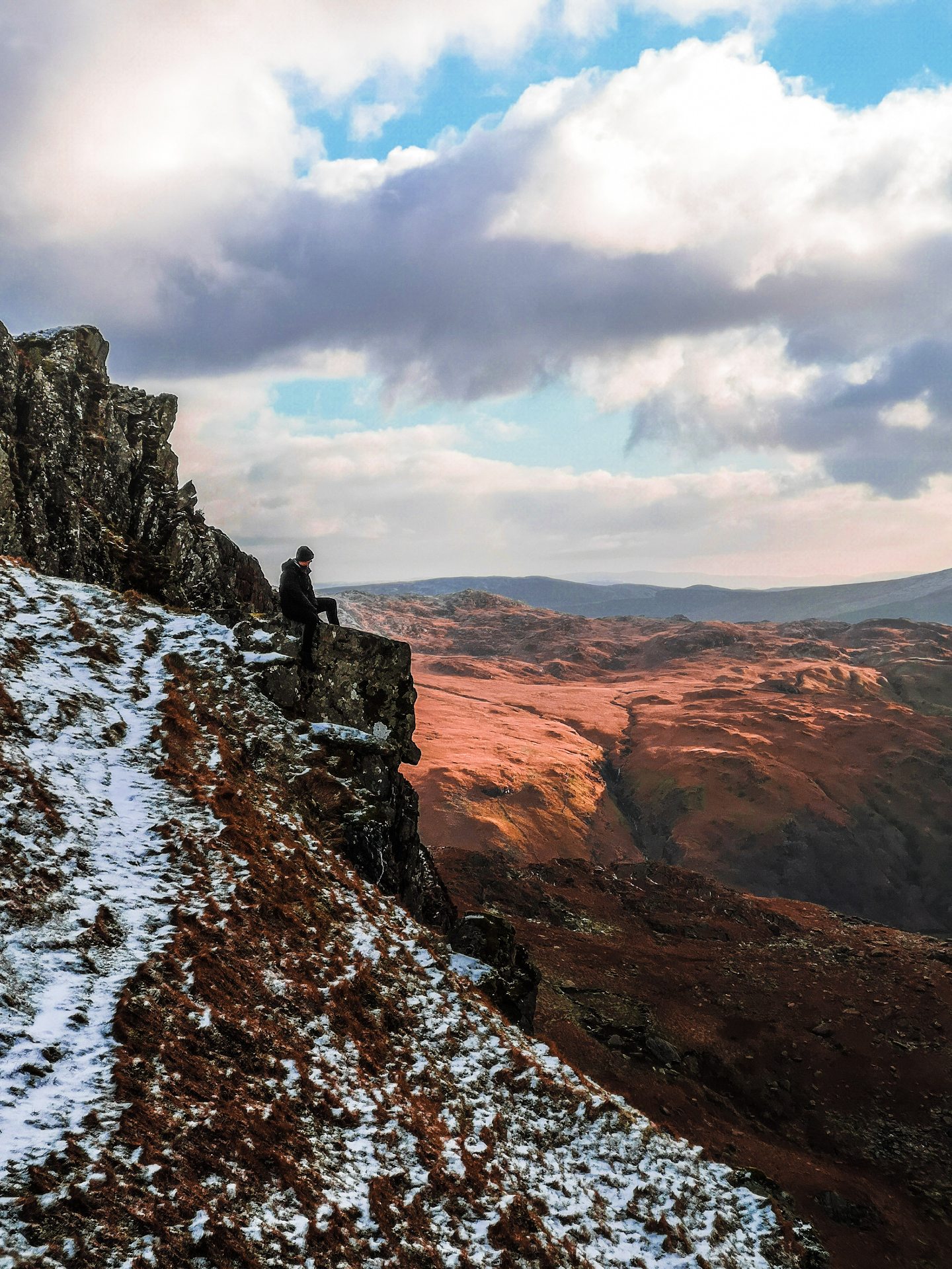 MAN SITTING ATOP RIDGE OVERLOOKING SNOWDONIA NATIONAL PARK