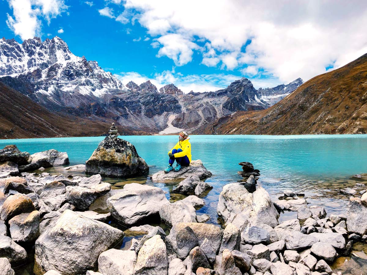Hiker sitting by aqua water Gokyo Lakes trek Nepal