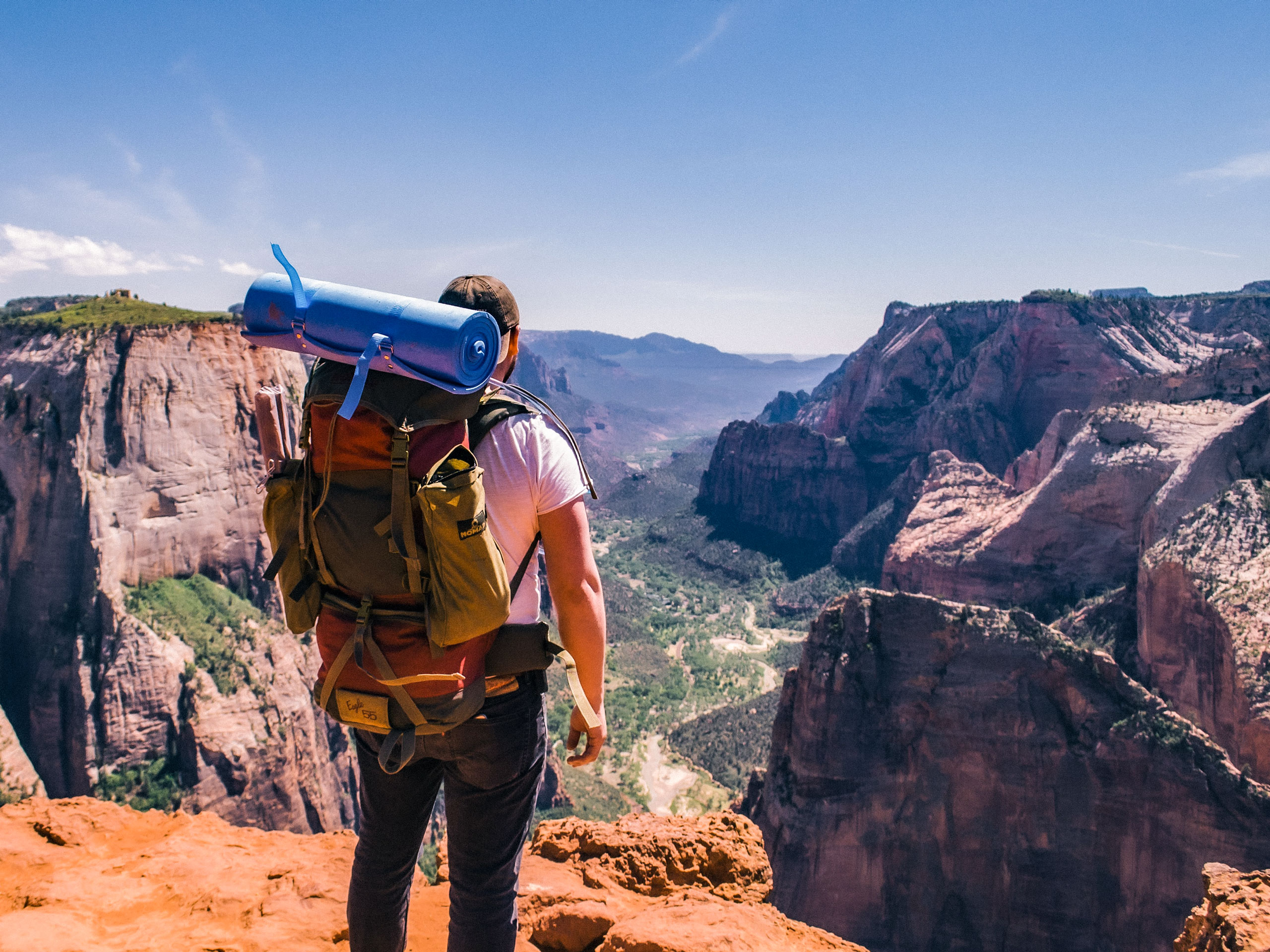 Man with backpack and camping gear standing above canyon