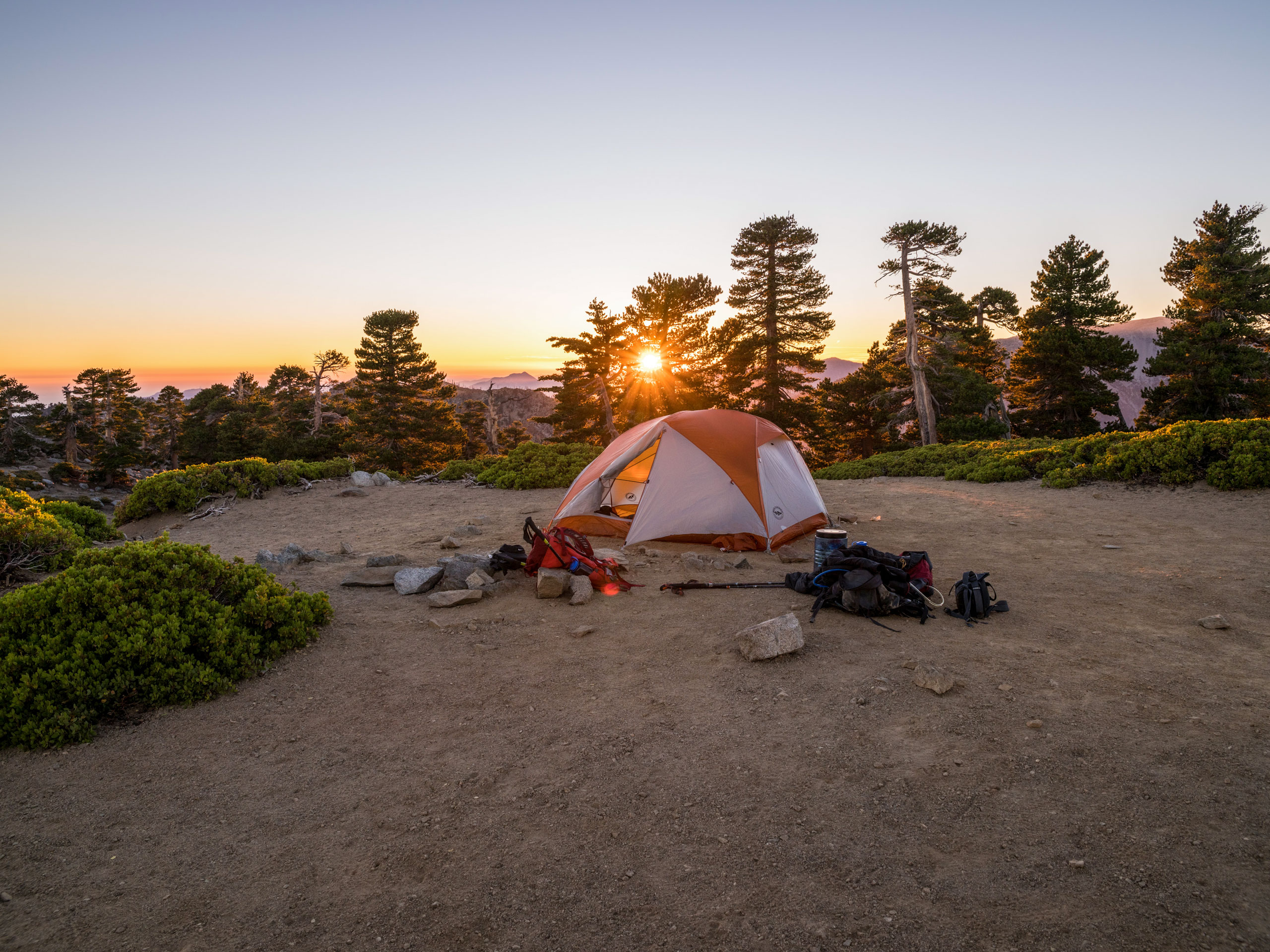 Sunrise sunset camping gear tent on mountain top lookout