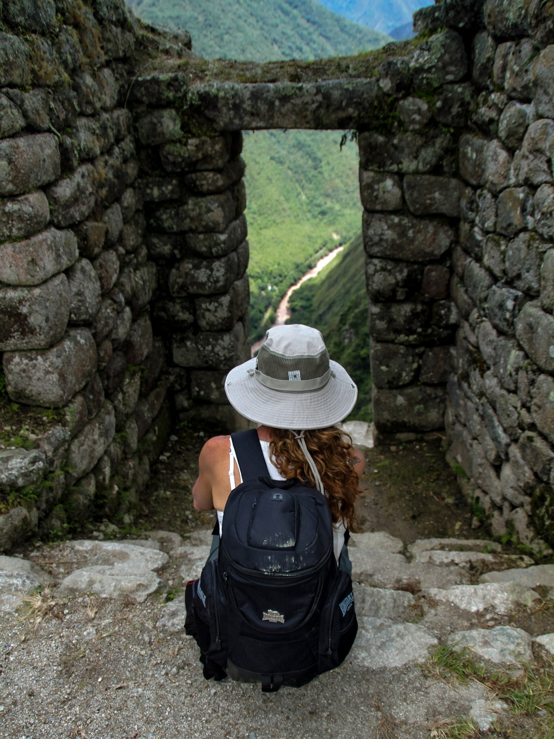 Hiker sitting on ancient stone steps Machu Picchu in Peru